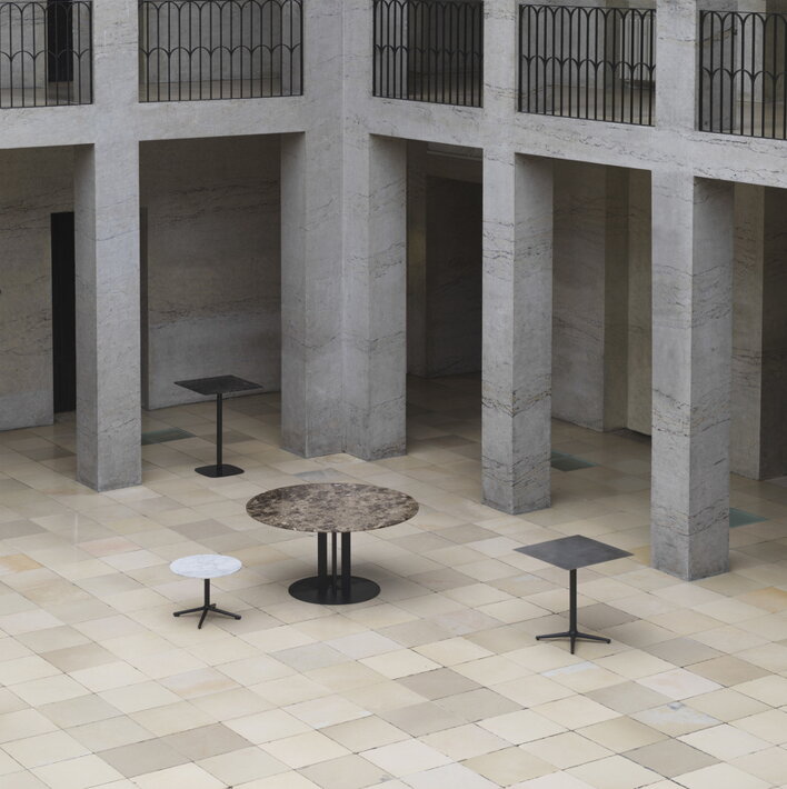 Štyri stoly rôznych tvarov a veľkostí na mramorovom nádvorí