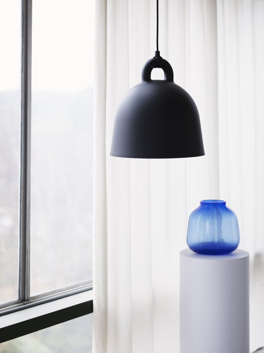 Stredná čierna závesná lampa v tvare zvonu nad dizajnovou vázou