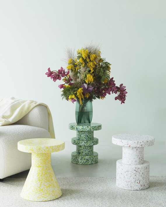 Viacúčelová taburetka zo zeleného recyklovaného plastu ako podstavec na dizajnovú vázu v obývačke