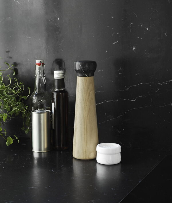 Vysoký drevený mlynček na čierne korenie s čiernym mramorom v dizajnovej čiernej kuchyni