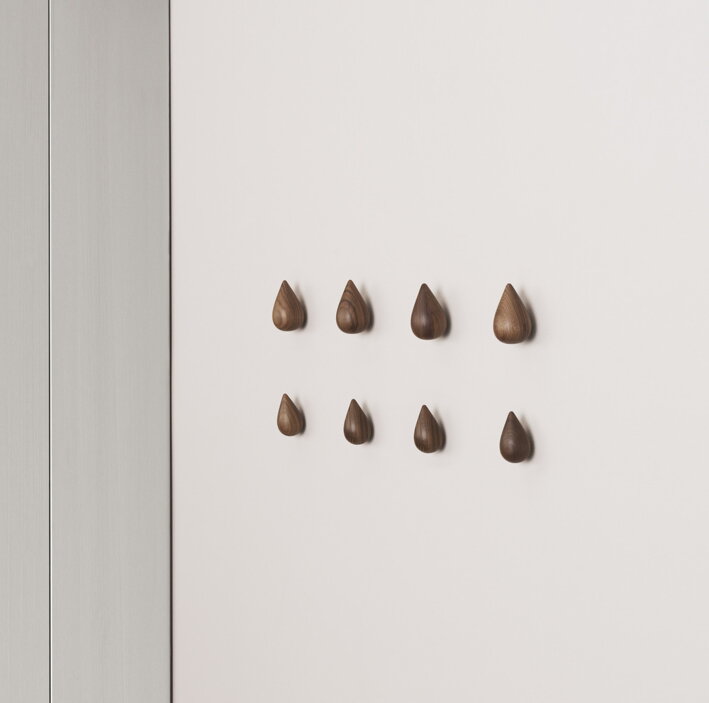 Veľké a malé háčiky z orechového dreva v tvare kvapky na stene v spálni