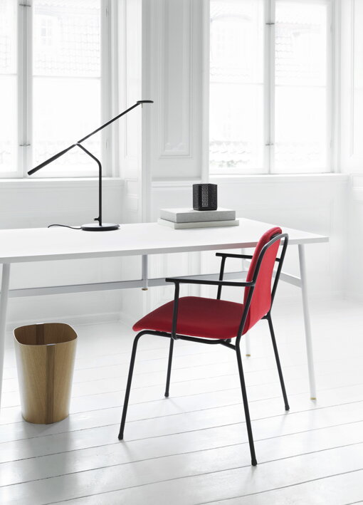 Dizajnová čierna lampa na pracovnom stole pri červenej stoličke