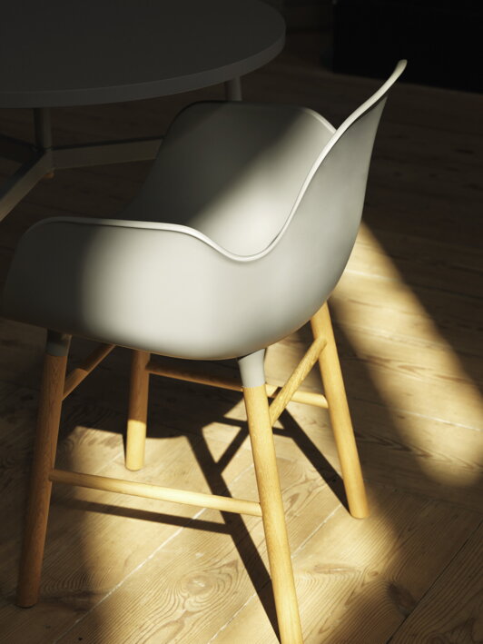 Bočný záber na sivú plastovú stoličku v tmavej miestnosti, na ktorú preniká slnečné žiarenie