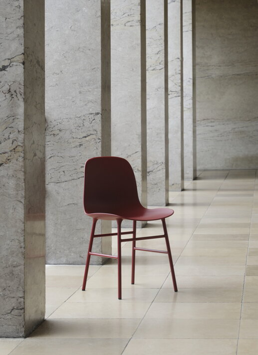 Červená jedálenská stolička s oceľovými nohami pri múriku v hale