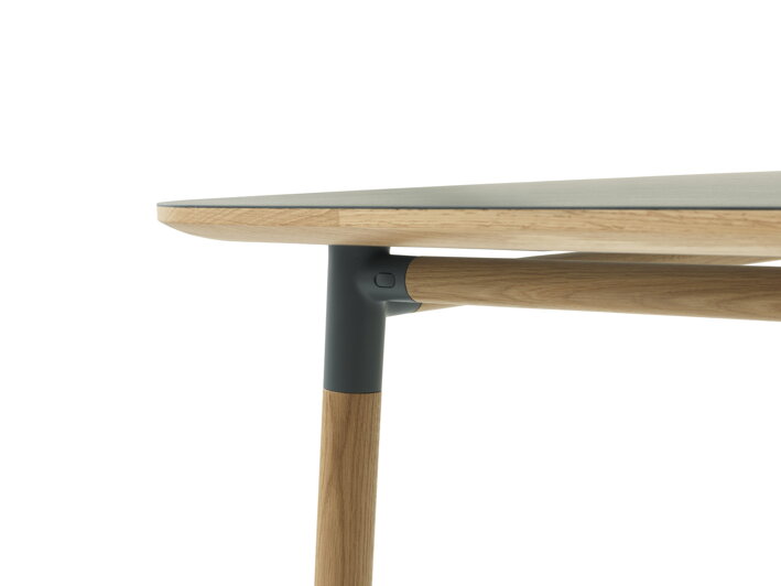 Detailný záber na dubovú nohu stola a linoleovú stolovú dosku