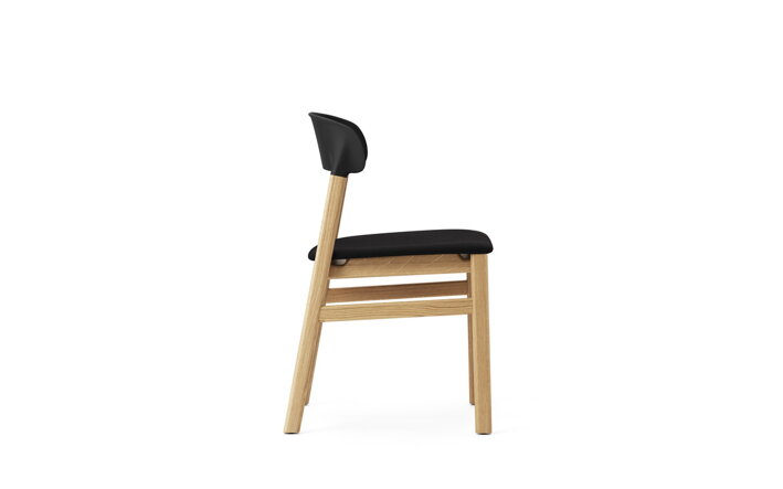 Detail bočnej strany čiernej stoličky s dubovými nohami a s čalúnením