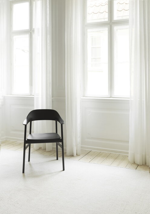 Čierna stolička pri okne v presvetlenej izbe