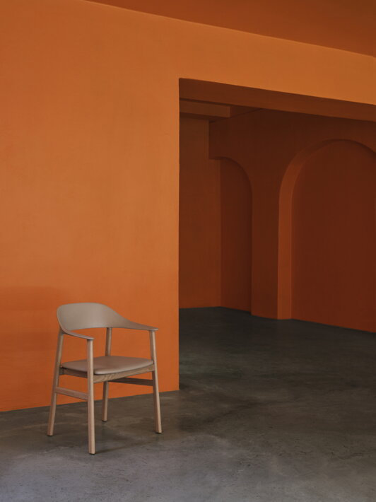 Piesková jedálenská stolička v hale s oranžovými stenami a sivou podlahou