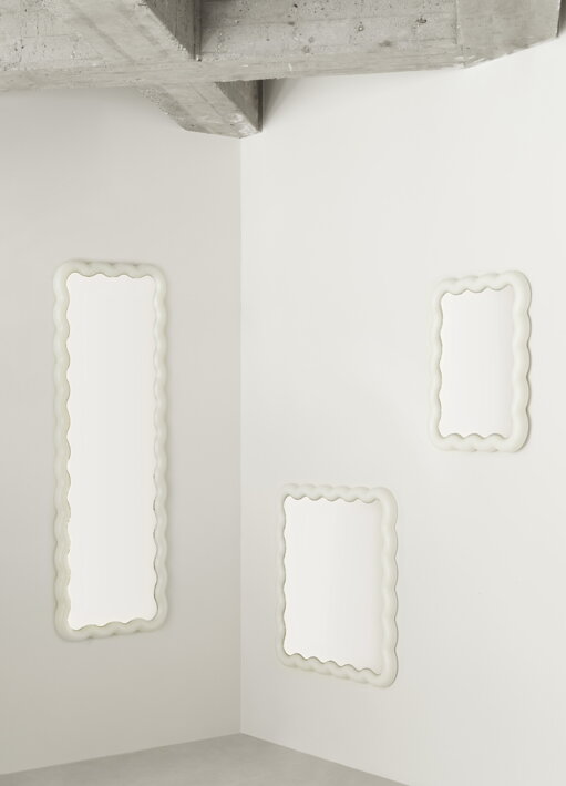 Tri biele nástenné zrkadlá rôznych veľkostí zavesené na bielej stene