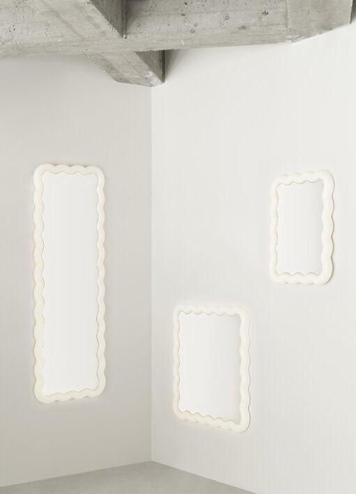 Tri biele nástenné zrkadlá s LED podsvietením rôznych veľkostí zavesené na bielej stene