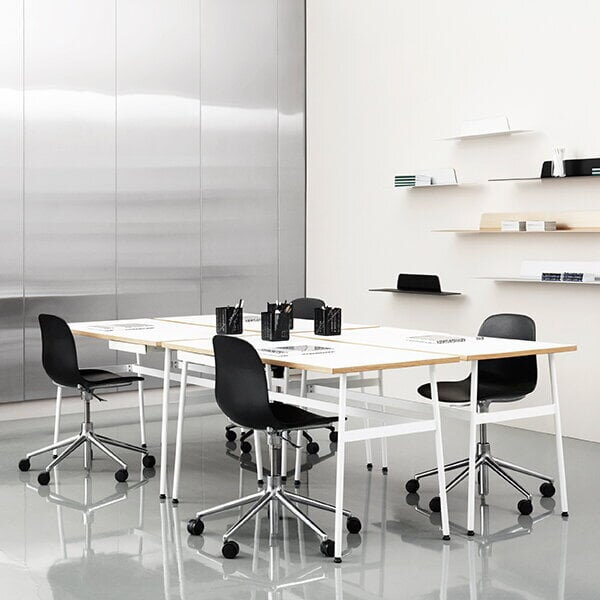 Viaceré nástenné police Jet rôznych farieb a veľkostí zavesené na stene v kancelárii, kde je biely stôl so štyrmi čiernymi kancelárskymi stoličkami.