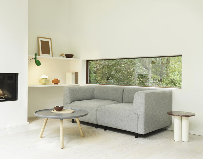 Drevený stolík vo svetlej obývačke vedľa sivej pohovky a krbu