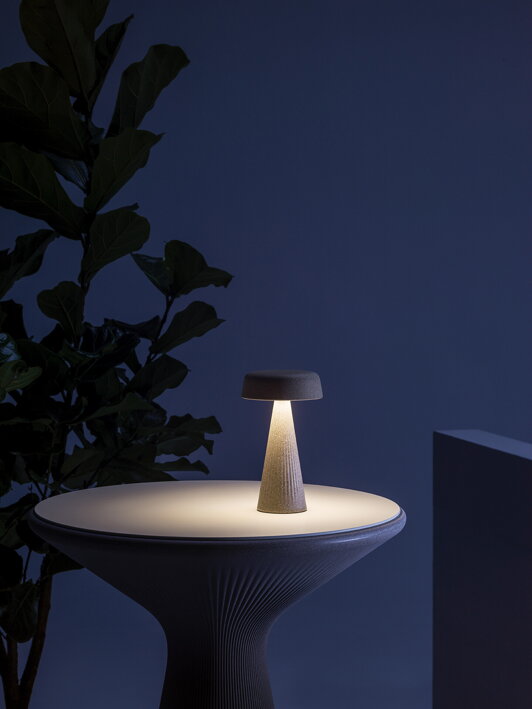 Dizajnová stolová lampa z odolného materiálu na stole na terase