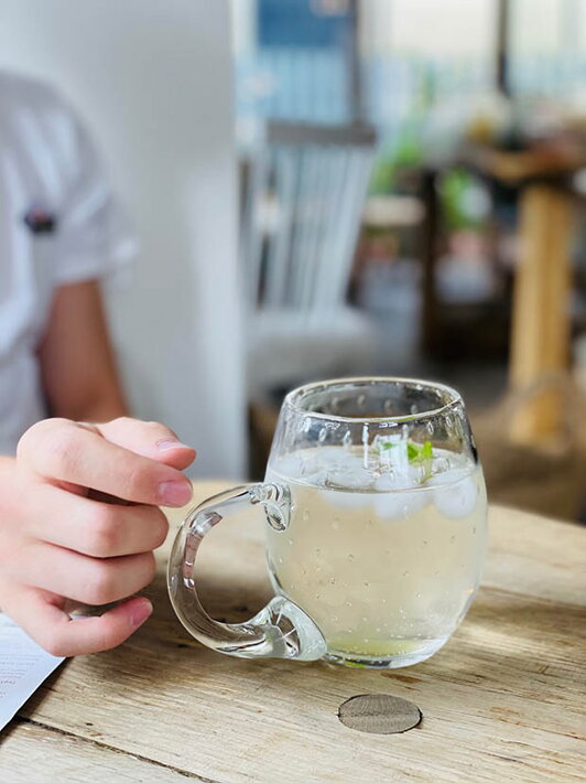 Malý ručne fúkaný pohár na pivo Slza na stole s osviežujúcim nápojom