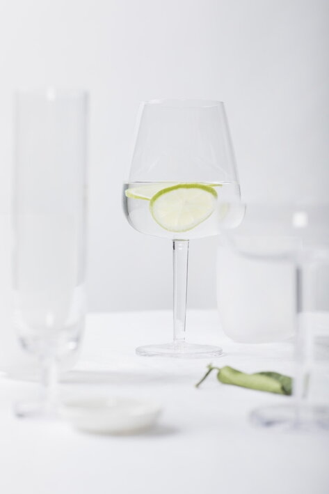 Oblý pohár na biele víno z tvrdeného skla s vodou a limetkou na bielom obruse