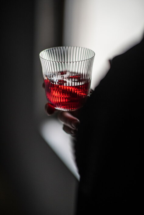 Dizajnér drží v ruke malý vrúbkovaný pohárik s červeným nápojom
