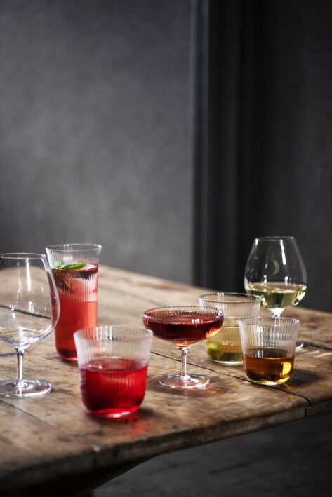 Rôzne ručne fúkané poháre z vrúbkovaného skla s farebnými nápojmi a drinkami