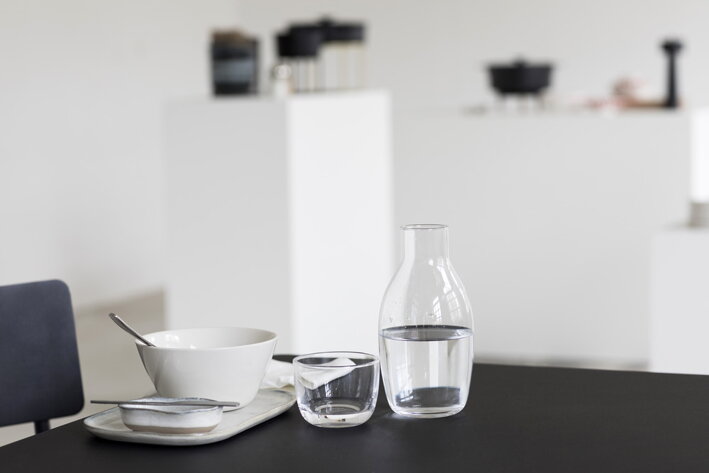 Karafa s vodou a nízky pohár na jedálenskom stole pri raňajkách