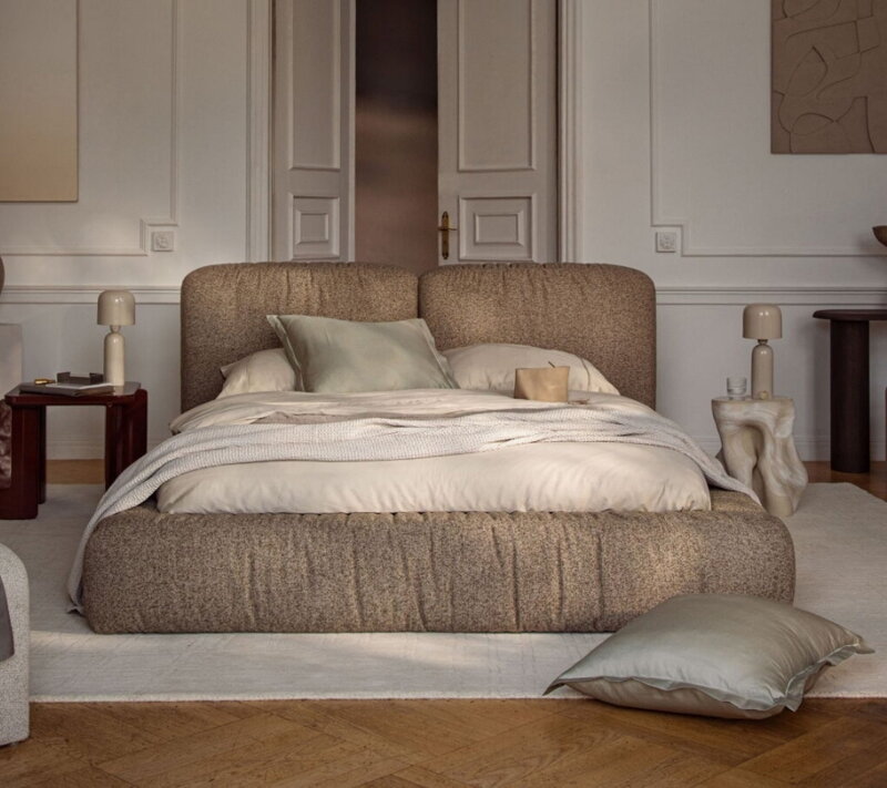 Čalúnená manželská posteľ svetlohnedej farby v dizajnovej spálni.