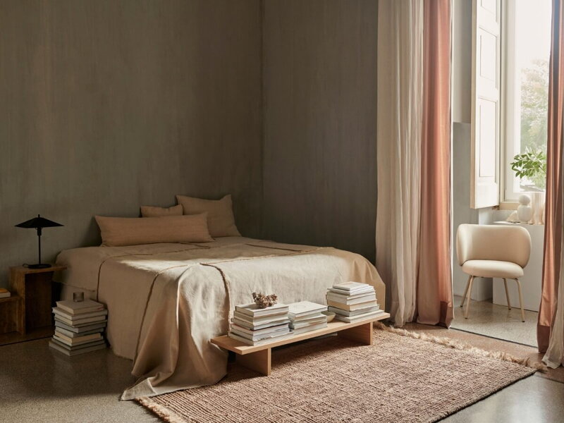 Ustlaná posteľ v minimalistickej spálni zariadenej v neutrálnych farbách.