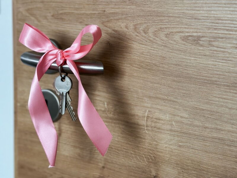Kľúče s ružovou mašľou na kľučke nového bytu.