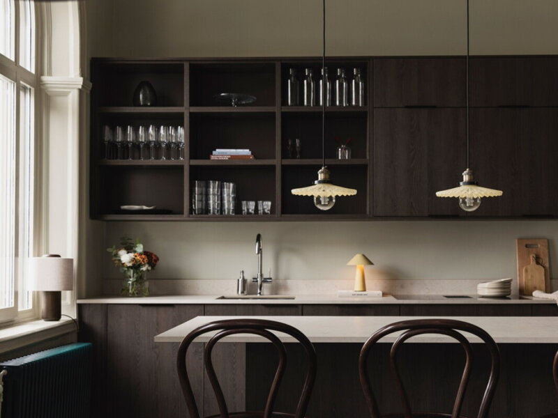 Závesné lampy s tienidlom z plisovaného skla krémovej farby nad kuchynským ostrovčekom.