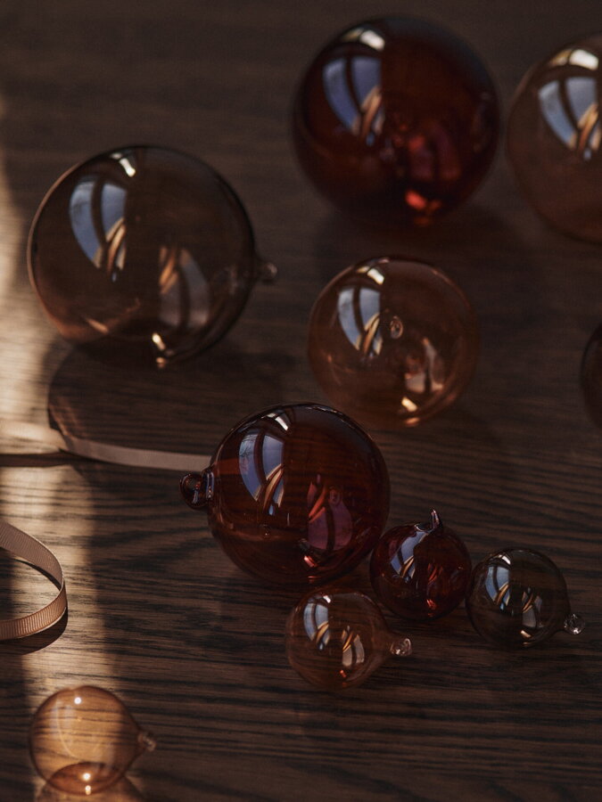 Vianočné gule Glass Baubles položené vedľa seba na drevenom povrchu.