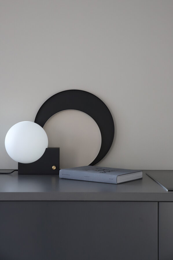 Čierny okrúhly podnos z kovu v pracovni pri knihe a lampe