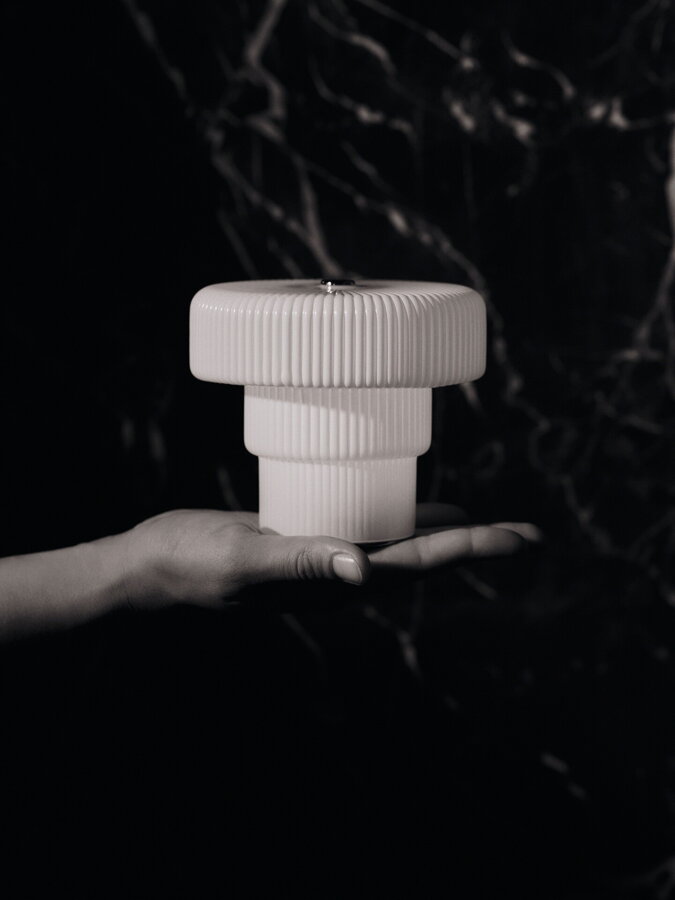 Prenosná lampa Ripple položená na ľudskej dlani.