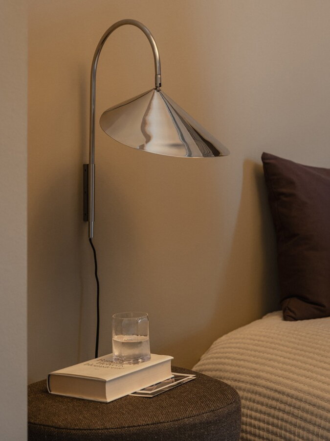 Nástenná nočná lampa nad nočným stolíkom vedľa postele.