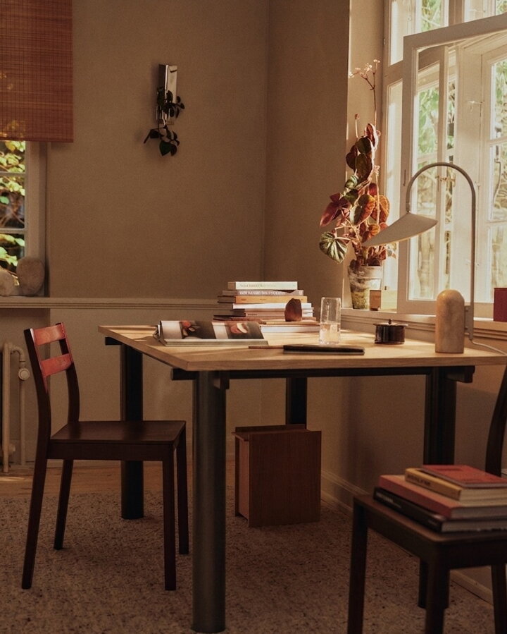 Jedálenský stôl so svetlou dubovou stolovou doskou a tmavohnedými kovovými nohami v domácej pracovni.