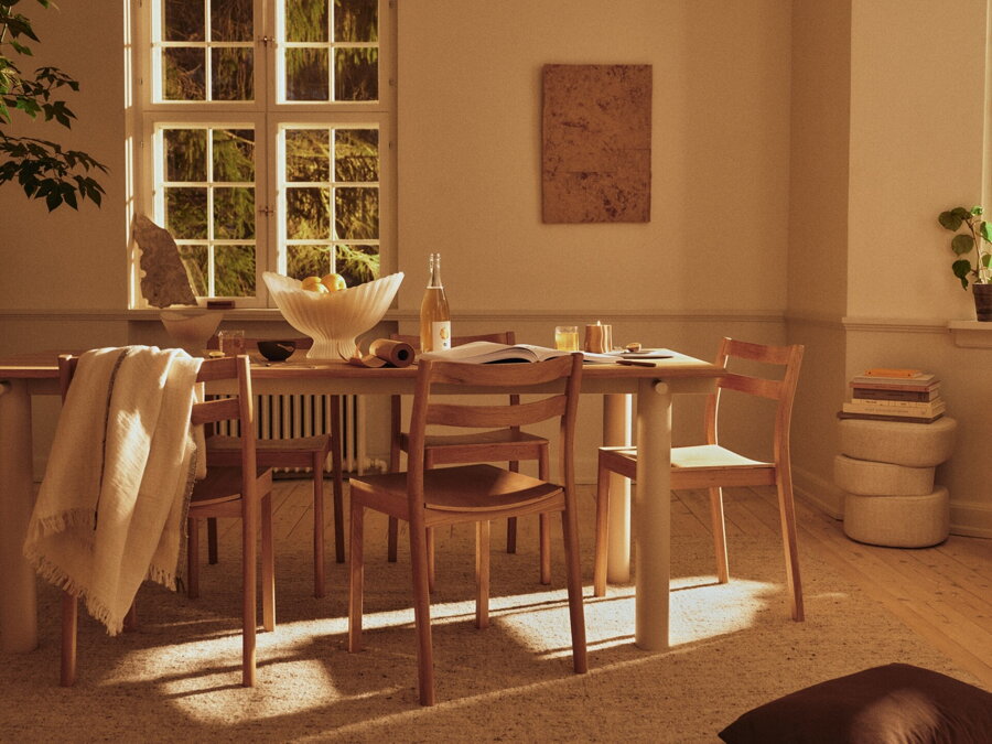 Prestretý svetlý dubový jedálenský stôl s béžovými oceľovými nohami v jedálni.