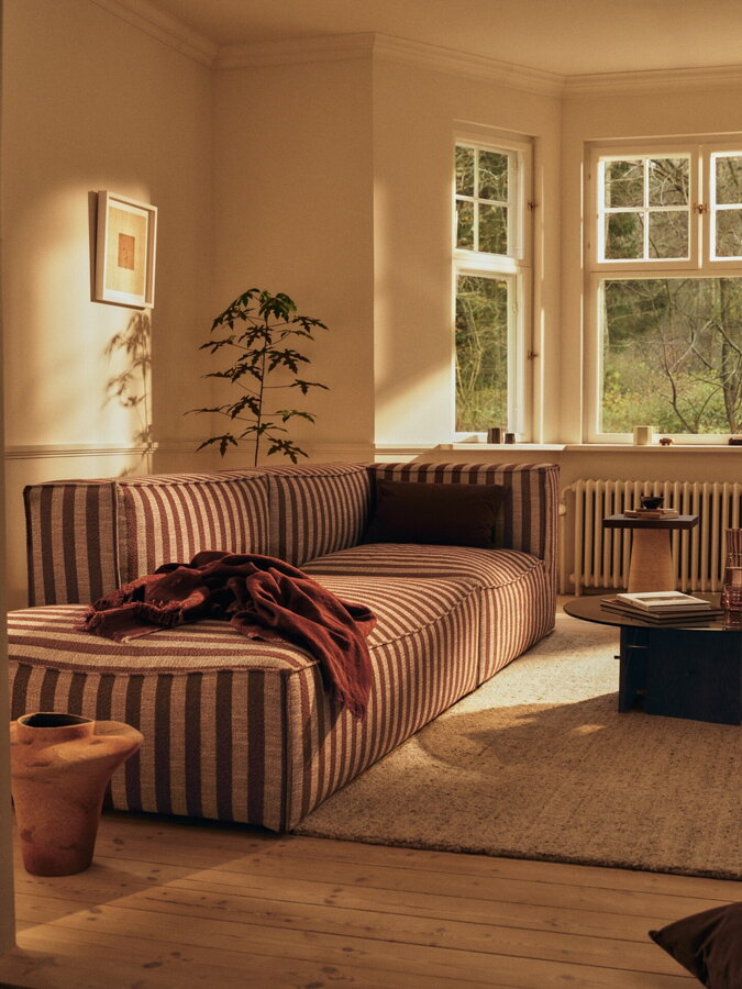 Pruhovaná pieskovo hnedá modulárna rohová sedačka v obývačke.