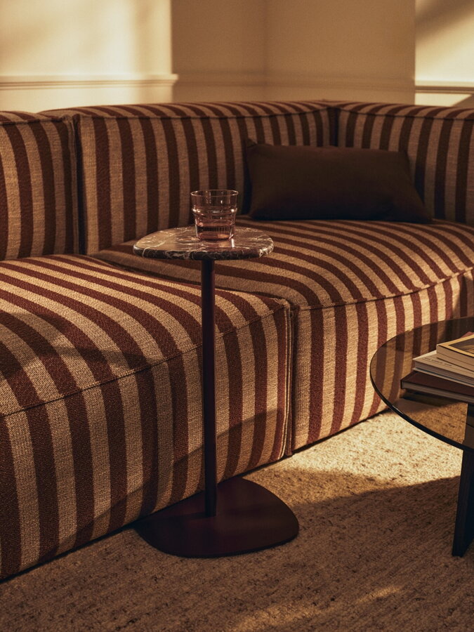 Pruhovaná pieskovo hnedá modulárna rohová sedačka s príručným stolíkom.