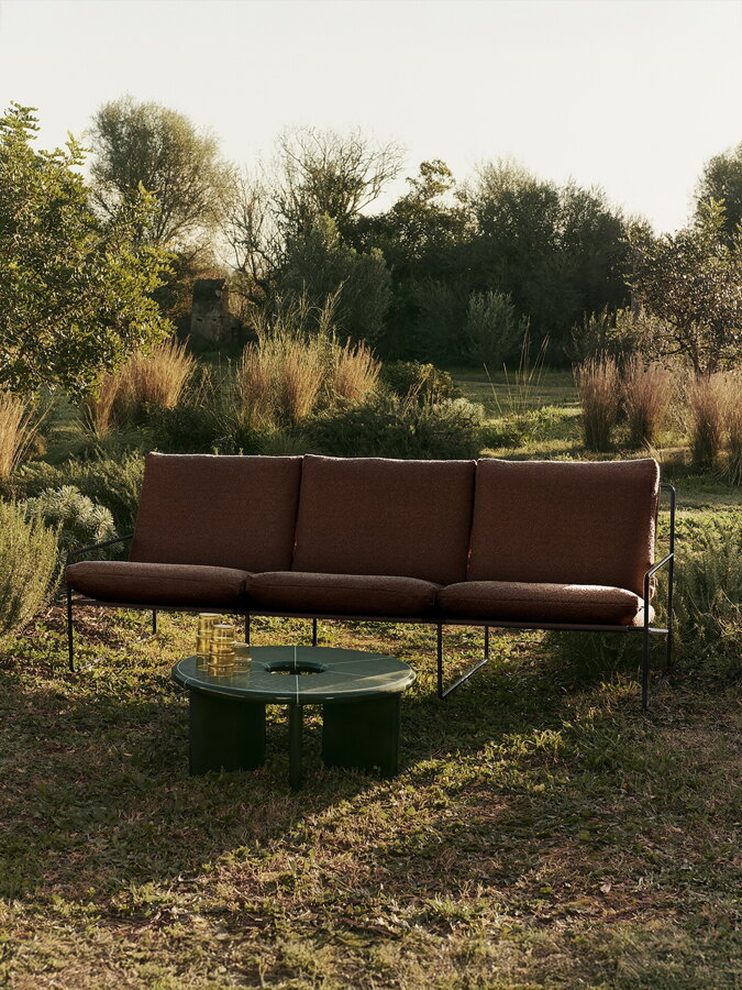 Tmavohnedá trojmiestna záhradná čalúnená pohovka v prírode.