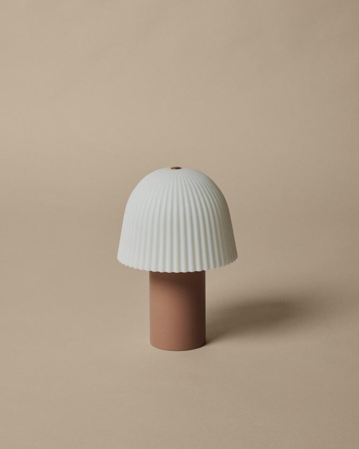 Ružová prenosná lampa Frill s bielym ryhovaným tienidlom.