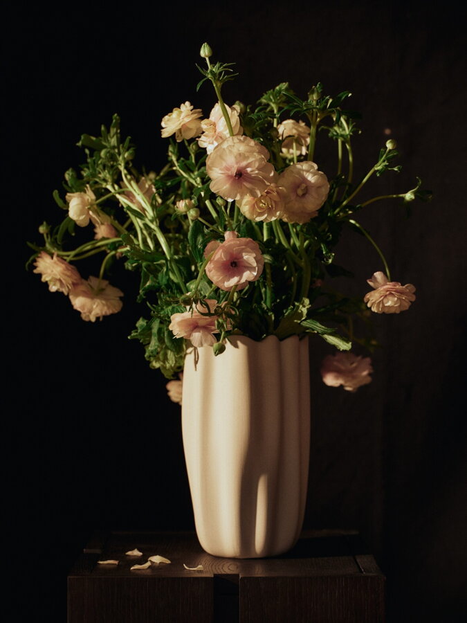 Biela kameninová váza Nium v tmavom prostredí s kyticou ružových kvetov.