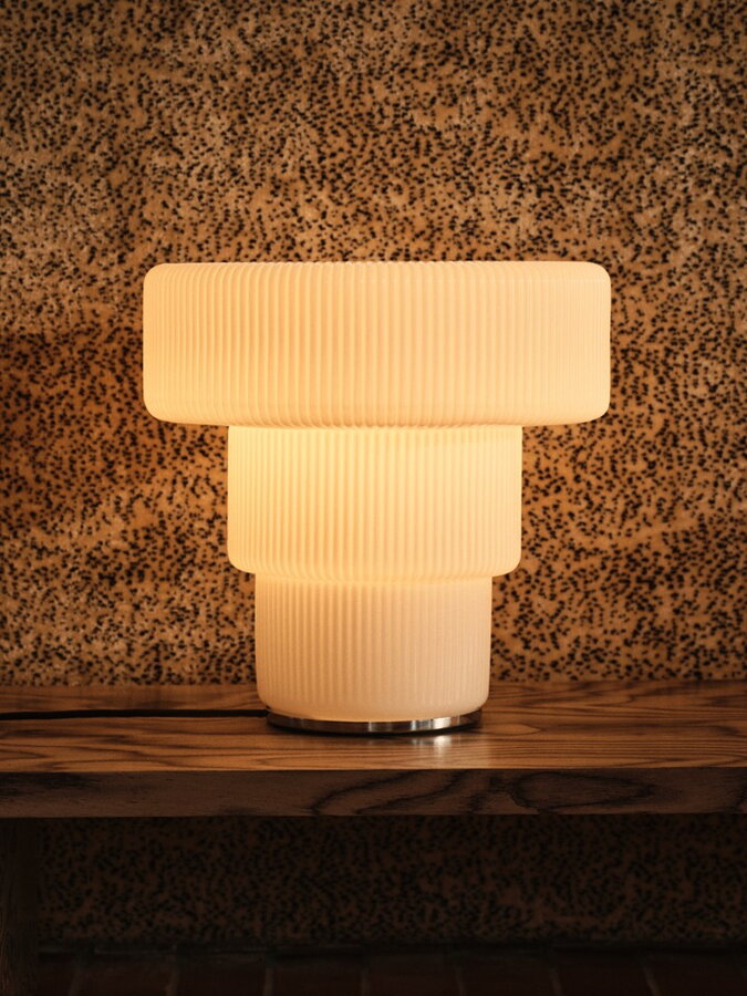 Svietiaca stolová lampa Ripple s telom z ručne fúkaného opálového skla s vlnitým povrchom bielej farby.