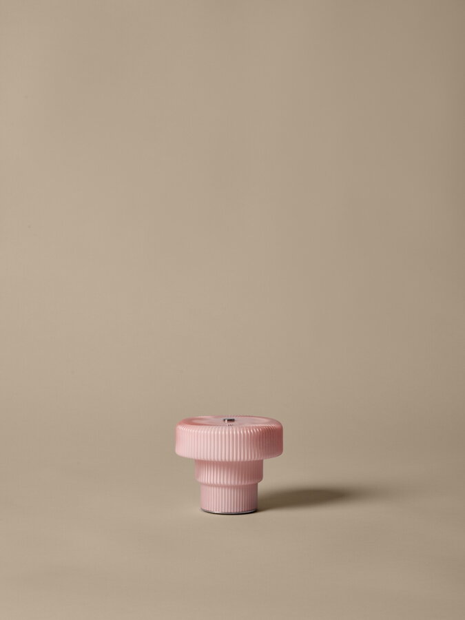 Prenosná lampa Ripple s telom z ručne fúkaného skla svetloružovej farby s vlnitým povrchom a tromi úrovňami jasu.