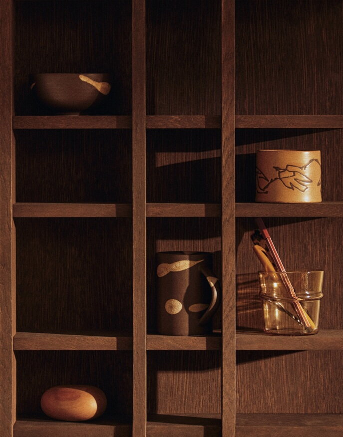 Drobné dekorácie a hrnčeky v otvorených policiach tmavohnedej police Tilem.