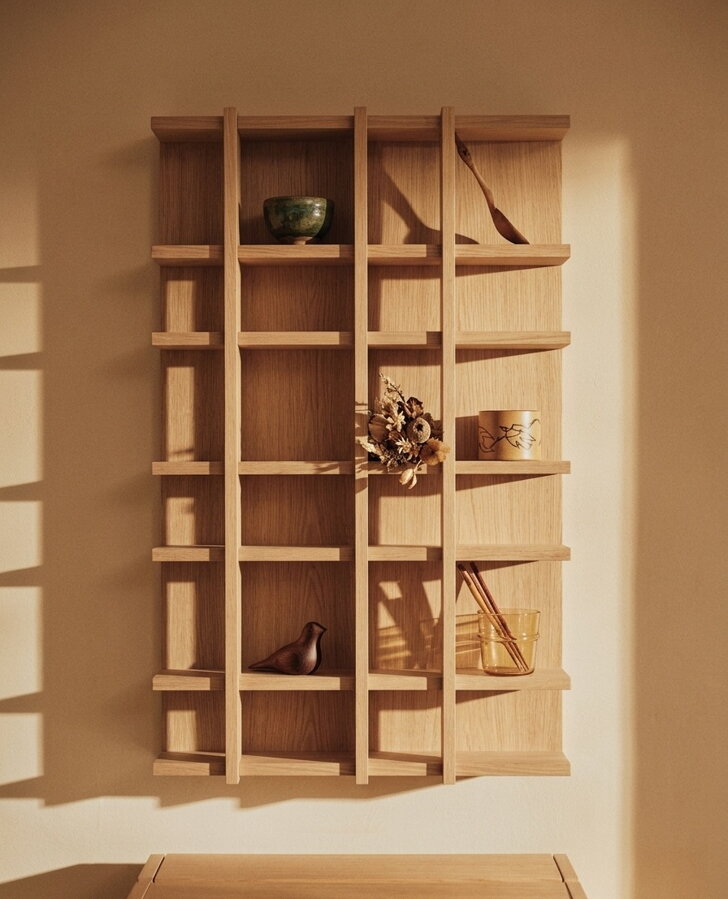 Rôzne drobné dekorácie, hrnčeky či suché kvety v otvorených priehradkach police Tilem, ktorá visí na stene.