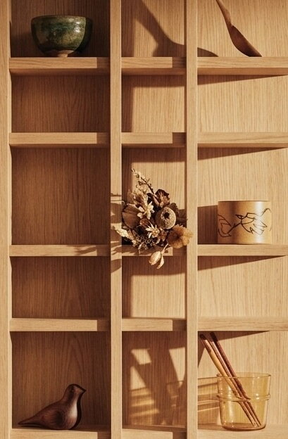 Rôzne drobné dekorácie, hrnčeky či suché kvety v otvorených priehradkach police Tilem.