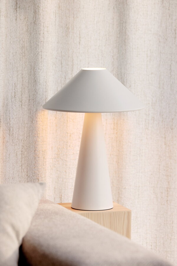 Svietiaca biela kovová stolová lampa.