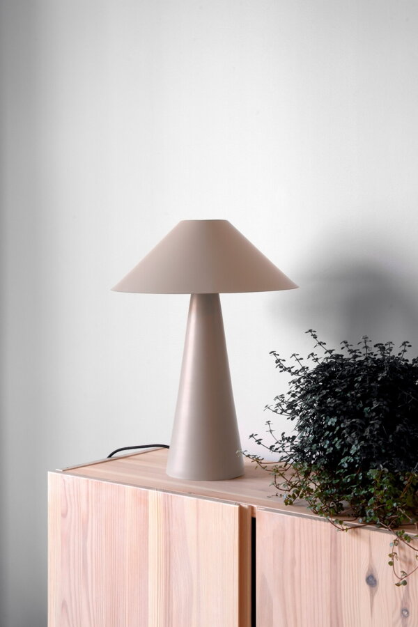 Svetlá hnedosivá kovová stolová lampa na drevenej skrinke.