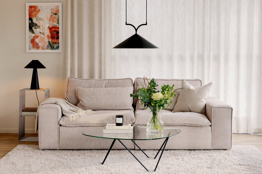 Čierna stolová lampa na príručnom stolíku v obývačke vedľa béžovej pohovky.