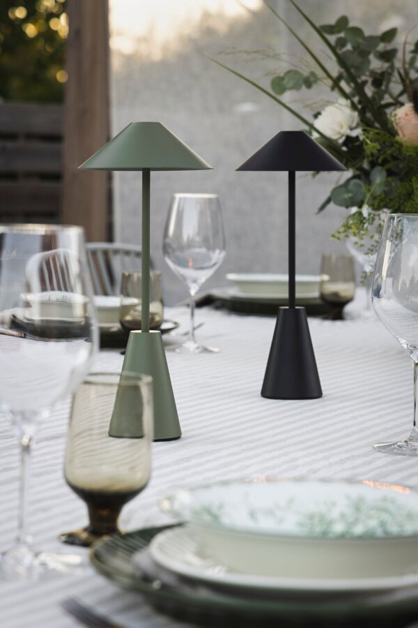 Zelená prenosná stolová lampa na prestretom jedálenskom stole.