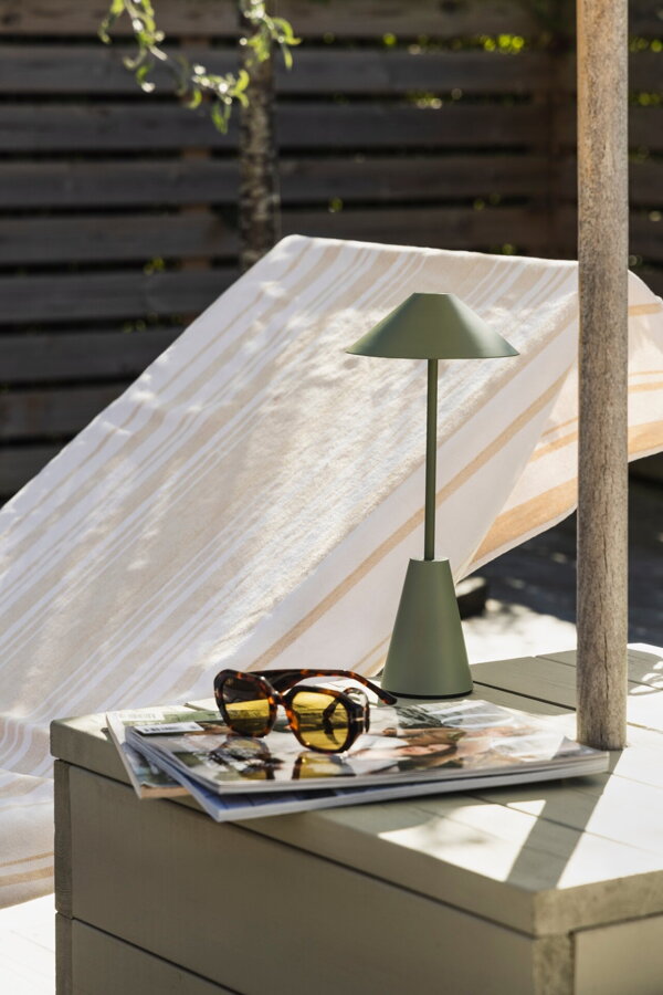 Zelená prenosná stolová lampa na záhradnom jedálenskom stole.