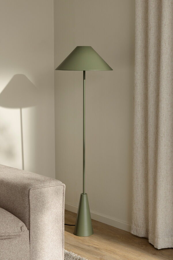 Zelená kovová stojanová lampa v rohu miestnosti vedľa béžovej pohovky.