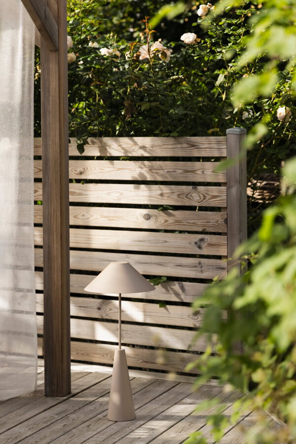 Hnedosivá prenosná stojanová lampa na terase v nastavenej najnižšej výške.