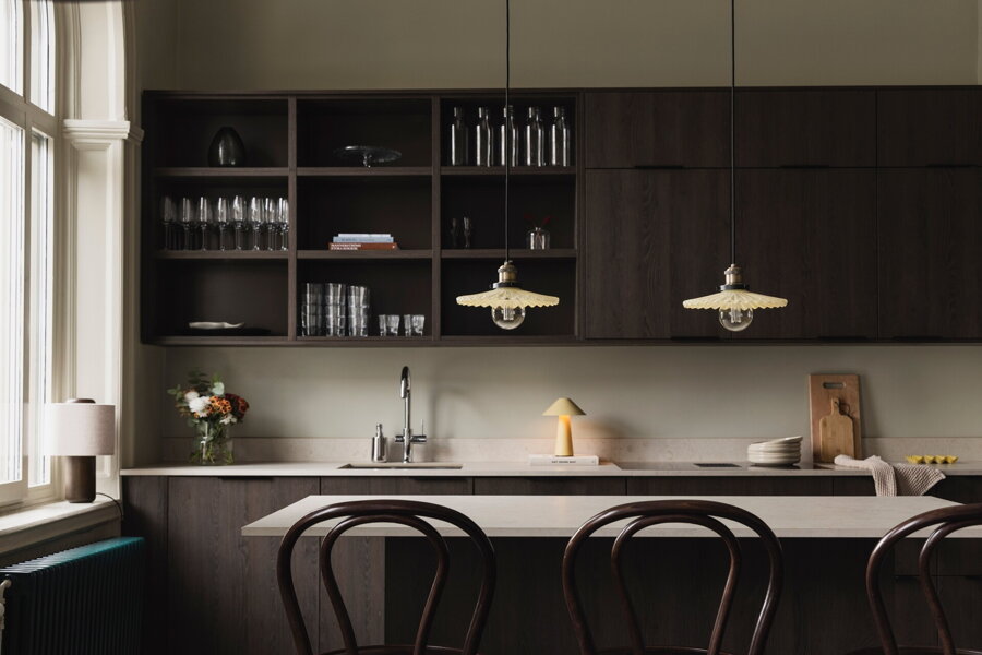 Dve závesné lampy Cobbler so skleneným tienidlom krémovej farby nad kuchynským ostrovčekom.